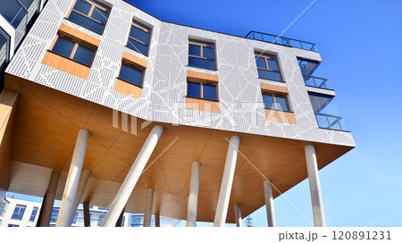 Modern high-rise apartment building  in white, stand tall against a blue sky, exemplifying innovative urban architecture with sleek, angular designs. 120891231