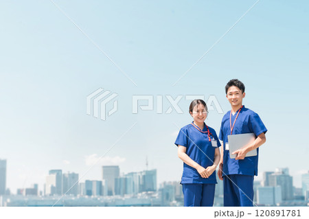 青空の下にいるスクラブ姿の医者・医師・看護師・医療従事者・ドクター・作業療法士・理学療法士の男女 青空の下にいるスクラブ姿の医者・医師・看護師・医療従事者・ドクター・作業療法士・理学療法士の男女 120891781