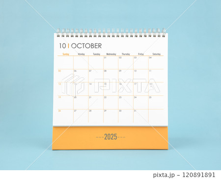 October 2025 white desk calendar on blue color background. 120891891