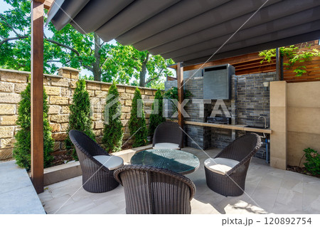 Backyard outdoor bbq zone with pergola, fireplace and hanging chair. Summer party place Backyard outdoor bbq zone with pergola, fireplace and hanging chair. Summer party place 120892754