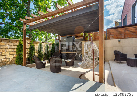 Backyard outdoor bbq zone with pergola, fireplace and hanging chair. Summer party place 120892756