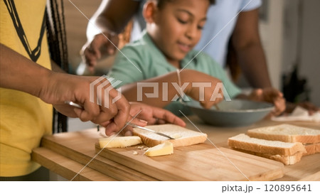 Crop woman applying butter on bread with brother whisking egg yolk in background 120895641