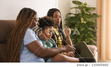 Happy family having popcorns while watching TV as they sit on sofa 120895660