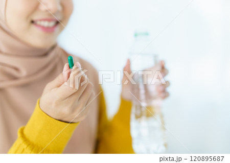 Asian young muslim woman showing a pill and water bottle, muslim woman taking a pill capsule. Health care and wellness in diverse ethnicity people and religious concept. Asian young muslim woman showing a pill and water bottle, muslim woman taking a pill capsule. Health care and wellness in diverse ethnicity people and religious concept. 120895687