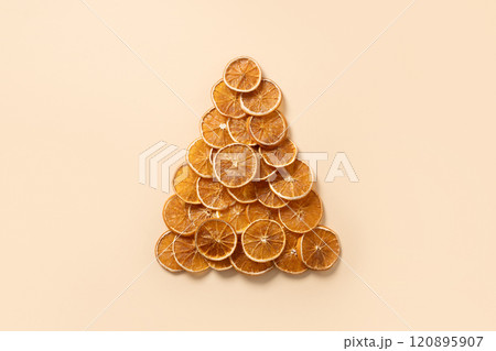 Eco-friendly creative Christmas tree made of natural dried orange slices on beige background. Food vegan. Happy New Year. View from above. Xmas greeting card. Eco-friendly creative Christmas tree made of natural dried orange slices on beige background. Food vegan. Happy New Year. View from above. Xmas greeting card. 120895907