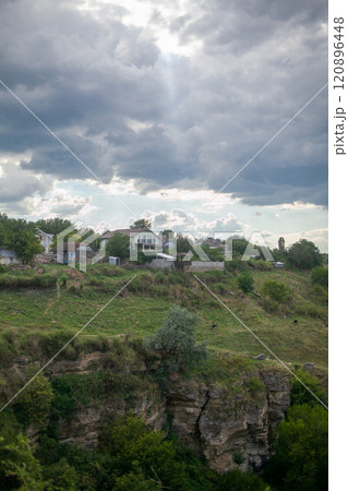 A village above a steep cliff under a gloomy sky A village above a steep cliff under a gloomy sky 120896448