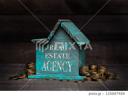 Wooden house model with coins next to it and hand 120897484
