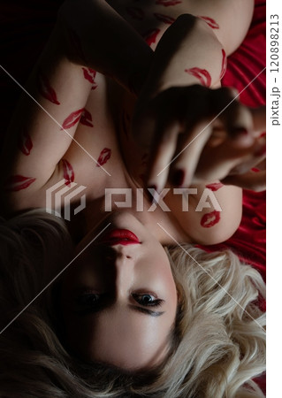 Woman poses topless with bodyart showing kisses in a sensual ambiance 120898213