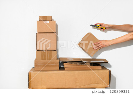 Pile of Cardboard Boxes and hand with cutter in Minimalist Setting Pile of Cardboard Boxes and hand with cutter in Minimalist Setting 120899331