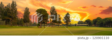 A golf course glowing under a dramatic sunset sky, surrounded by lush trees and vibrant colors, offering a breathtaking view. A golf course glowing under a dramatic sunset sky, surrounded by lush trees and vibrant colors, offering a breathtaking view. 120901110