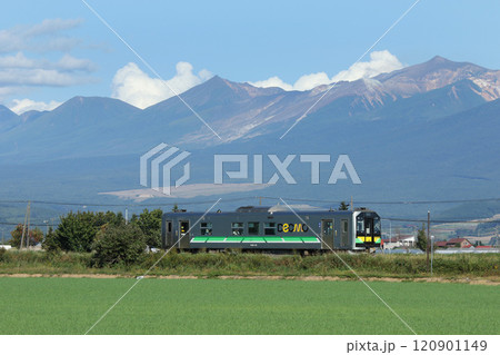 十勝岳連山をバックに駆ける富良野線普通列車　H100　DECMO 120901149