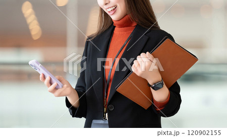 スマホとバインダーを持つ笑顔の女性・ビジネスウーマン 120902155