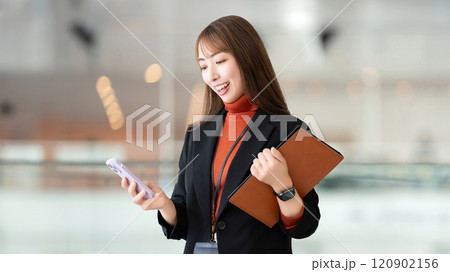 スマホとバインダーを持つ笑顔の女性・ビジネスウーマン 120902156