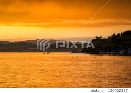 Scenic orange yellow sunset on the lake in a bay with yachts Scenic orange yellow sunset on the lake in a bay with yachts 120902327