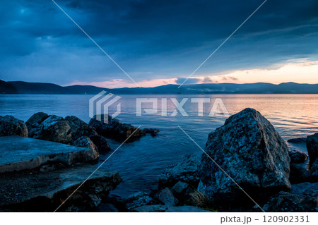 Large blocks of stones on the shore of the lake against the backdrop of a beautiful sunset Large blocks of stones on the shore of the lake against the backdrop of a beautiful sunset 120902331