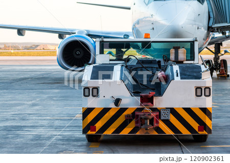 The tow truck drive up at the passenger aircraft parked to a jet bridge 120902361