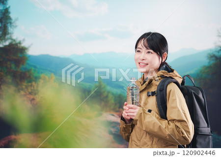 登山をしながら水分補給をする若い女性 登山をしながら水分補給をする若い女性 120902446