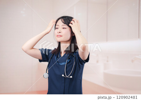 化粧室で身だしなみを整える医療従事者の女性 120902481