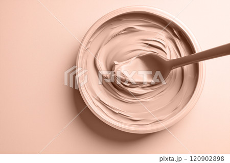 Mocha mousse beige face mask scooped with a spatula on a smooth background. Modern trendy tone hue shade 120902898