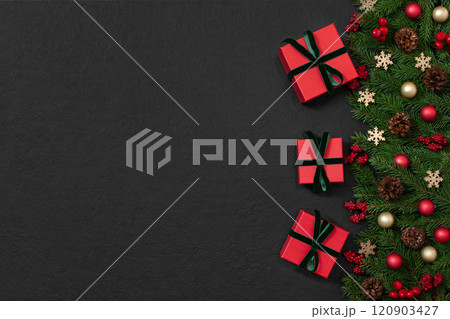Christmas border with gifts, fir branches and festive decor on black background. New Year background with copy space. Top view, flat lay. 120903427