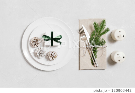 New Year table setting with gifts, fir branches, candles and cones on white background. Christmas table. Top view, flat lay. New Year table setting with gifts, fir branches, candles and cones on white background. Christmas table. Top view, flat lay. 120903442