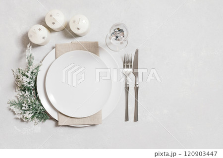 Christmas serving with empty white plate, candles and silverware on white background. Beautiful New Year table setting with copy space. Top view, flat lay. 120903447