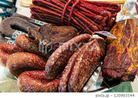 Various delicious jerky gammon and sausages on dish, top view. Traditional ready-to-eat meat products on the counter in the market. Various delicious jerky gammon and sausages on dish, top view. Traditional ready-to-eat meat products on the counter in the market. 120903544