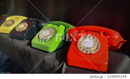 Retro wired phones of different colors on a black background. Concept of modern technologies, outdated devices Retro wired phones of different colors on a black background. Concept of modern technologies, outdated devices 120905244