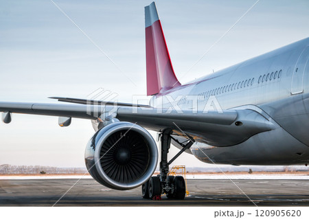 Close-up of wing, engine, main landing gear, fuselage and tail fins of wide-body passenger aircraft 120905620