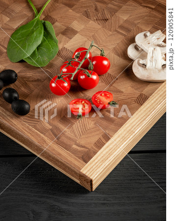 A cutting board for cooking on a black wooden background. Beautiful pattern of squares, oak material. A cutting board for cooking on a black wooden background. Beautiful pattern of squares, oak material. 120905841