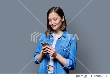 Young smiling woman using smartphone in grey background 120906094