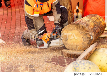 Mastering the art of chainsaw cutting at a lumberjack festival in the autumn sun 120906518