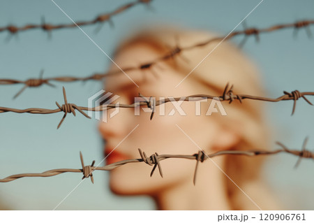 Barbed wire with a blurred woman in the background 120906761