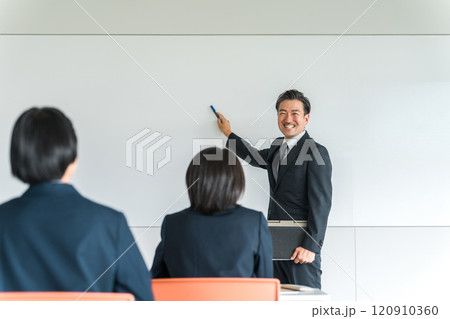 会議・塾・セミナー・勉強会・説明会で先生・講師・教師・ビジネスマンからプレゼンを受ける女性 120910360