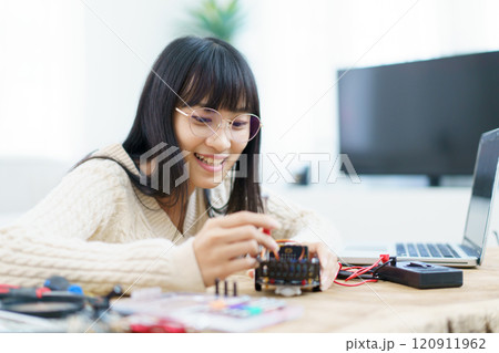 Happy cheerful Asian ethnicity female university student learning about robotic and programing by herself, woman assemble a robot and coding. Happy cheerful Asian ethnicity female university student learning about robotic and programing by herself, woman assemble a robot and coding. 120911962