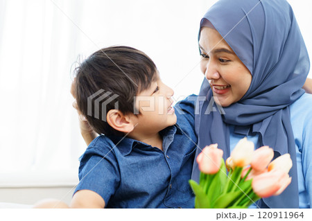 Happy cheerful Asian muslim family living together in a weekend, woman muslim embracing her lovely little son and smiling to camera. Modern muslim lifestyles concept. 120911964