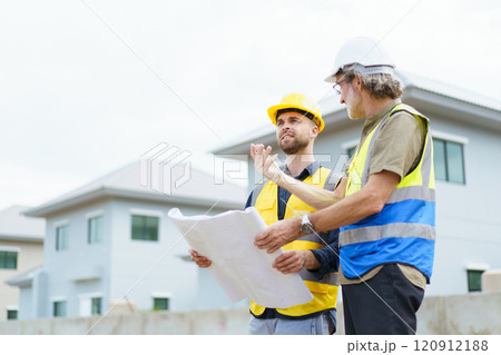 Engineers or construction contractors discussing together at the empty land about construction plan. Man talking to real estate contractor on building blueprint. Engineers or construction contractors discussing together at the empty land about construction plan. Man talking to real estate contractor on building blueprint. 120912188