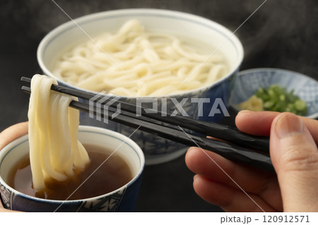 うどん 熱々のあつもりうどん 釜揚げうどんをつゆにつけて箸で持ち上げる うどん 熱々のあつもりうどん 釜揚げうどんをつゆにつけて箸で持ち上げる 120912571