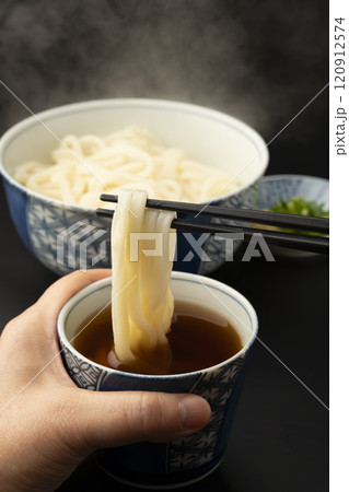 うどん　熱々のあつもりうどん　釜揚げうどんをつゆにつけて箸で持ち上げる 120912574