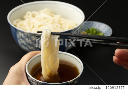 うどん 熱々のあつもりうどん 釜揚げうどんをつゆにつけて箸で持ち上げる うどん 熱々のあつもりうどん 釜揚げうどんをつゆにつけて箸で持ち上げる 120912575