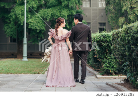式場の庭を歩くカラードレス姿とスーツ姿の男女カップル（結婚式・ウェディング・ブライダル） 120913288