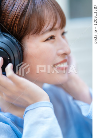 ヘッドホンで音楽を聴くショートボブの若い女性 120913387