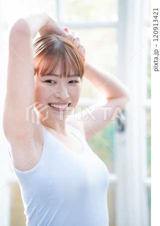 朝日を浴びるタンクトップを着たショートボブの若い女性 120913421