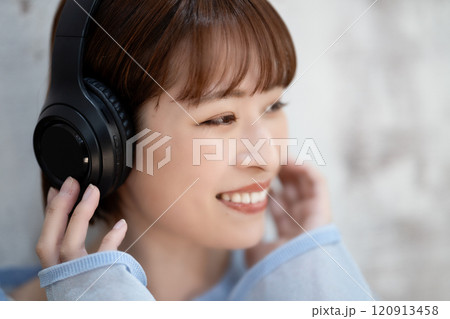 ヘッドホンで音楽を聴くショートボブの若い女性 120913458