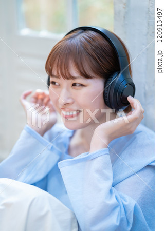 ヘッドホンで音楽を聴くショートボブの若い女性 120913497