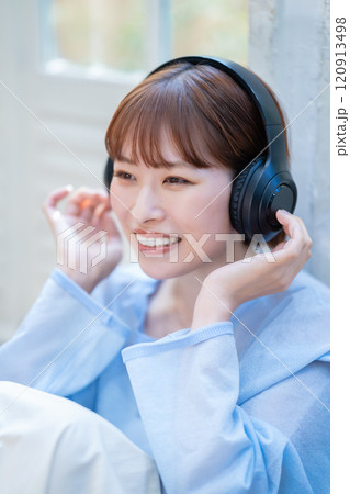 ヘッドホンで音楽を聴くショートボブの若い女性 120913498