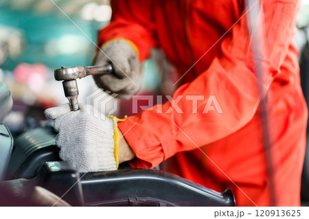 Automobile technician working in auto garage, technician holding a wrench preparing to repair broken vehicle. Professional auto or car repairman fixing a crashed car. Automobile technician working in auto garage, technician holding a wrench preparing to repair broken vehicle. Professional auto or car repairman fixing a crashed car. 120913625