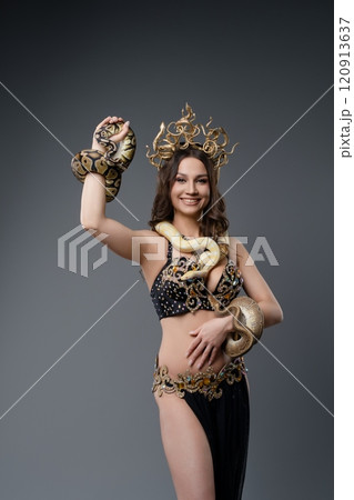 Woman in elaborate costume poses with snakes in a studio setting Woman in elaborate costume poses with snakes in a studio setting 120913637