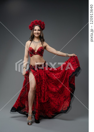 Belly dancer performing in a vibrant red costume with floral accessories Belly dancer performing in a vibrant red costume with floral accessories 120913640