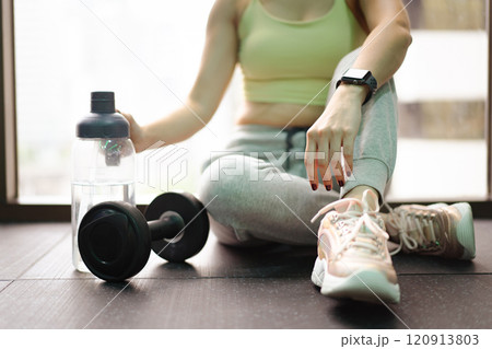 Good looking - beautiful Asian woman relaxing in the gym after made weight training and cardio workout, woman sitting or resting on the bench while drinking water after exercise. Good looking - beautiful Asian woman relaxing in the gym after made weight training and cardio workout, woman sitting or resting on the bench while drinking water after exercise. 120913803